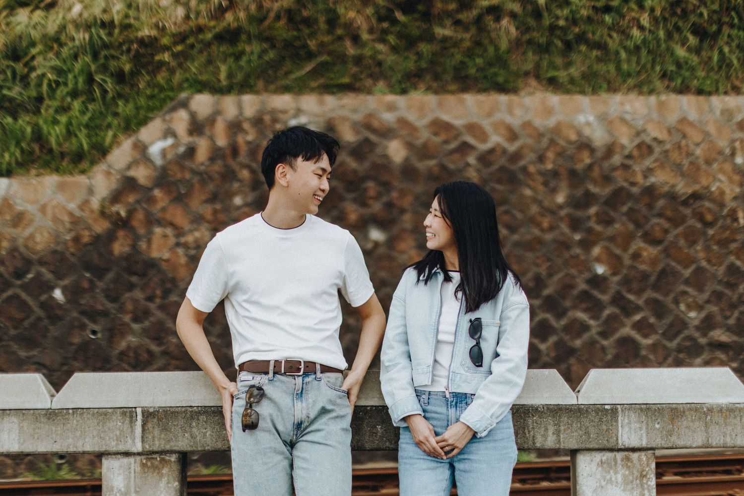 Casual couples photoshoot on stone steps in matching white and denim outfits.