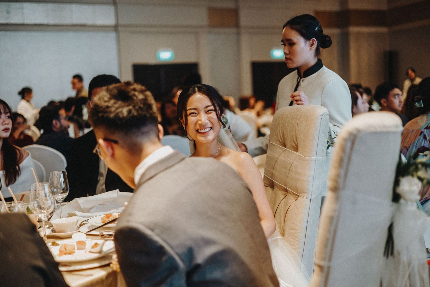 A candid reception moment with guests and servers in a hotel ballroom.