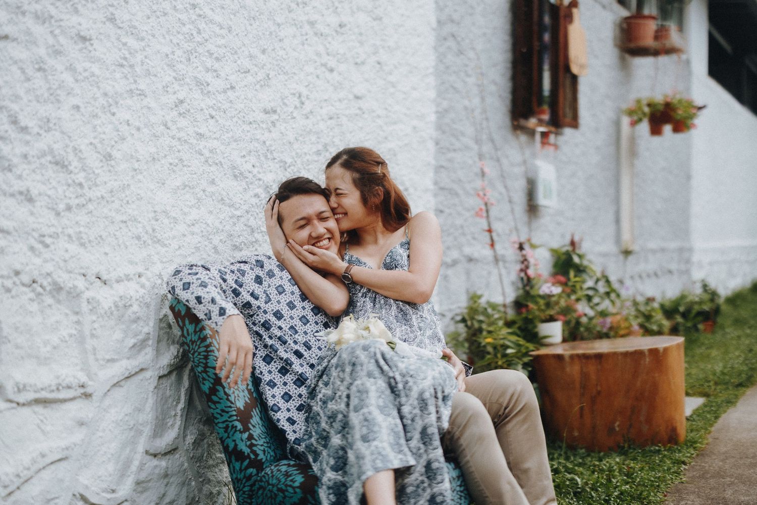 Couple in coordinated outfits shares intimate moments against a textured white wall.