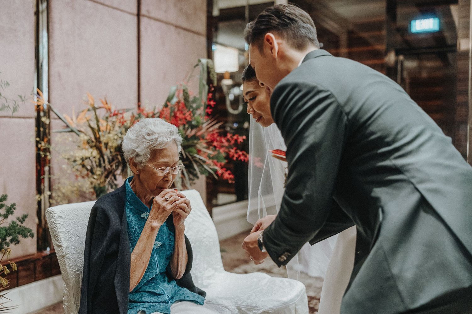 An emotional moment between two people at a formal event with red flowers in the background.