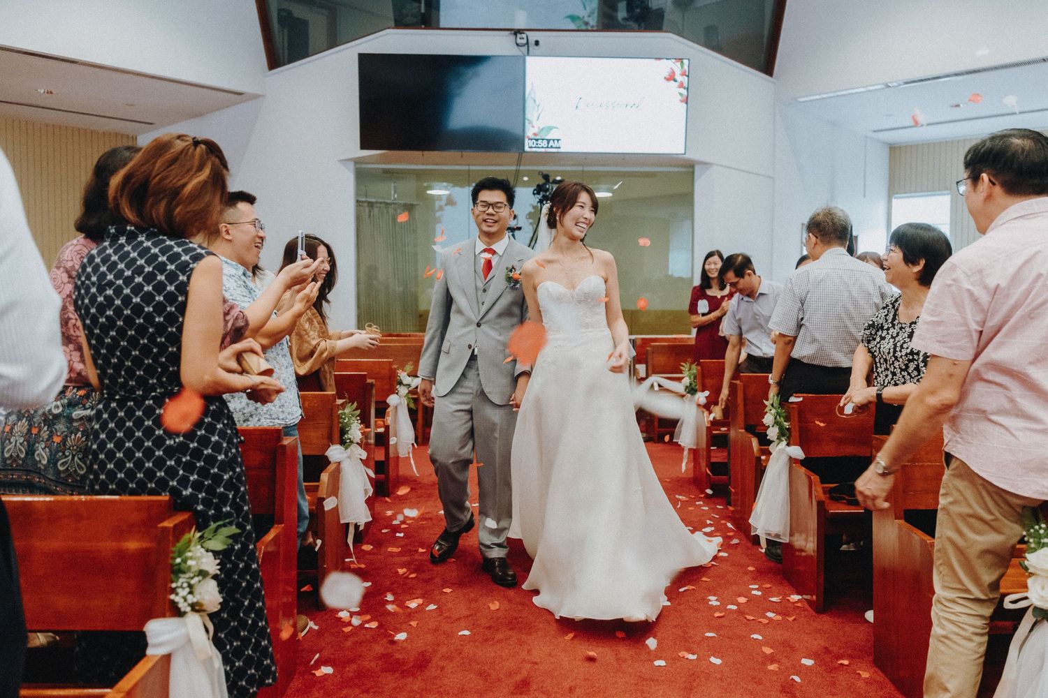 Wedding guests line the red-carpeted church aisle as newlyweds make their exit.