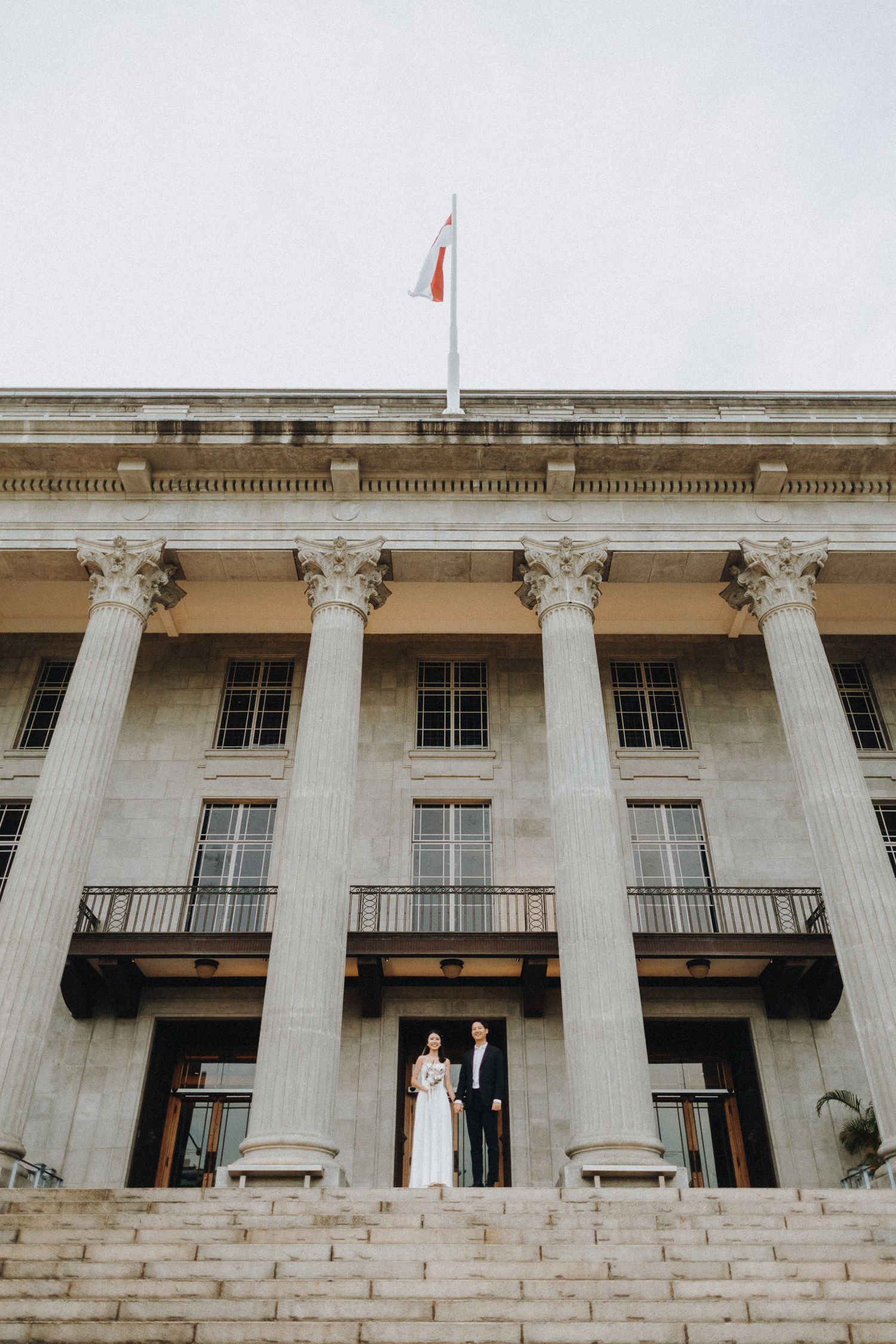 Majestic white neoclassical building exterior with tall Corinthian columns and grand stone steps leading to entrance.
