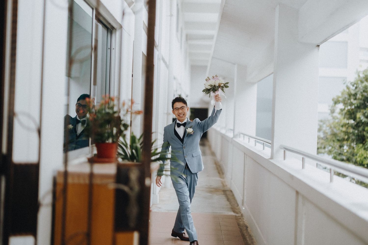 A joyful moment captured in a bright white corridor with decorative plants.