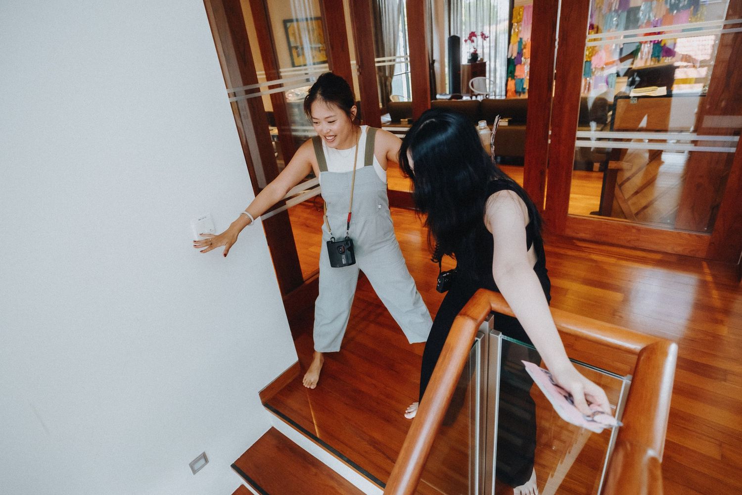 Two people practicing dance moves on a wooden floor in a mirrored studio.