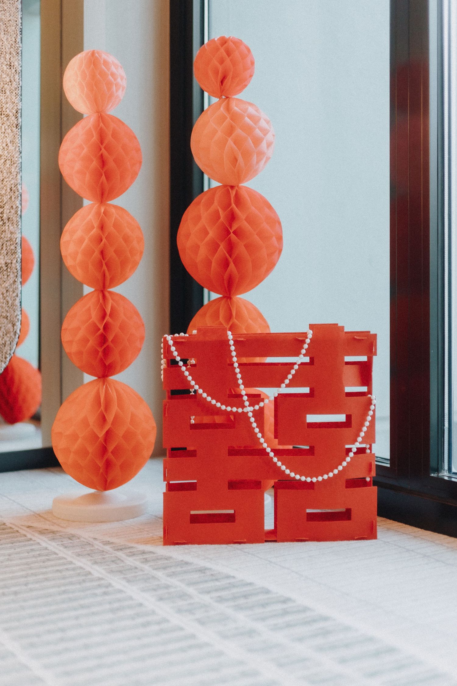Traditional Chinese wedding decorations with red double happiness symbols and orange paper lanterns line a bright hallway.
