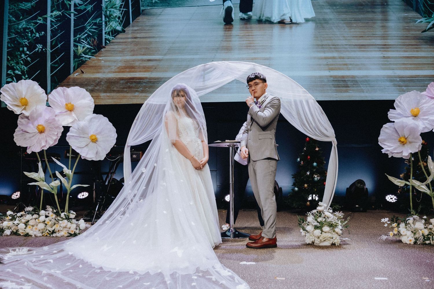 A wedding ceremony setup with white floral decorations and a long flowing veil.