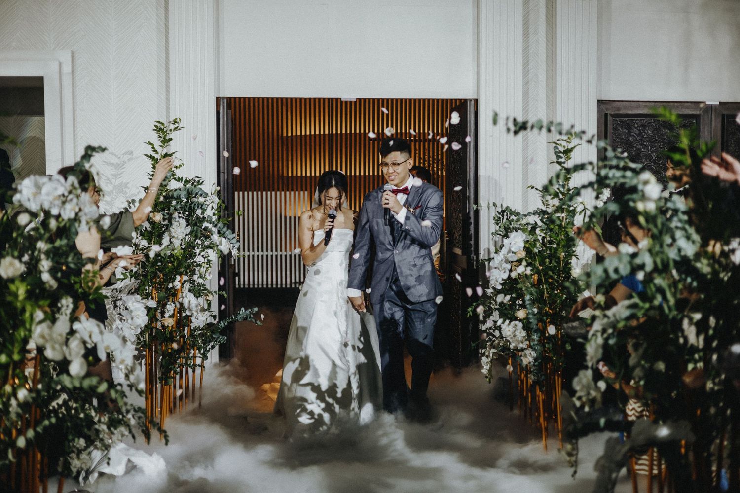 Wedding ceremony setup with white floral arrangements and wooden accents in an indoor venue.