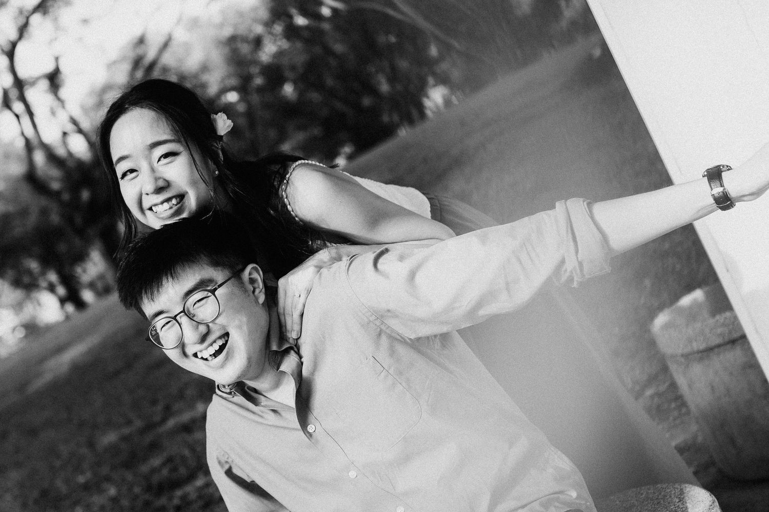 A playful black and white image showing a happy couple having fun outdoors in a natural setting.