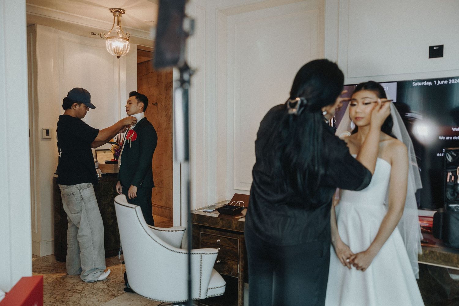 Wedding preparation scene in a hotel room with black suit and white dress.