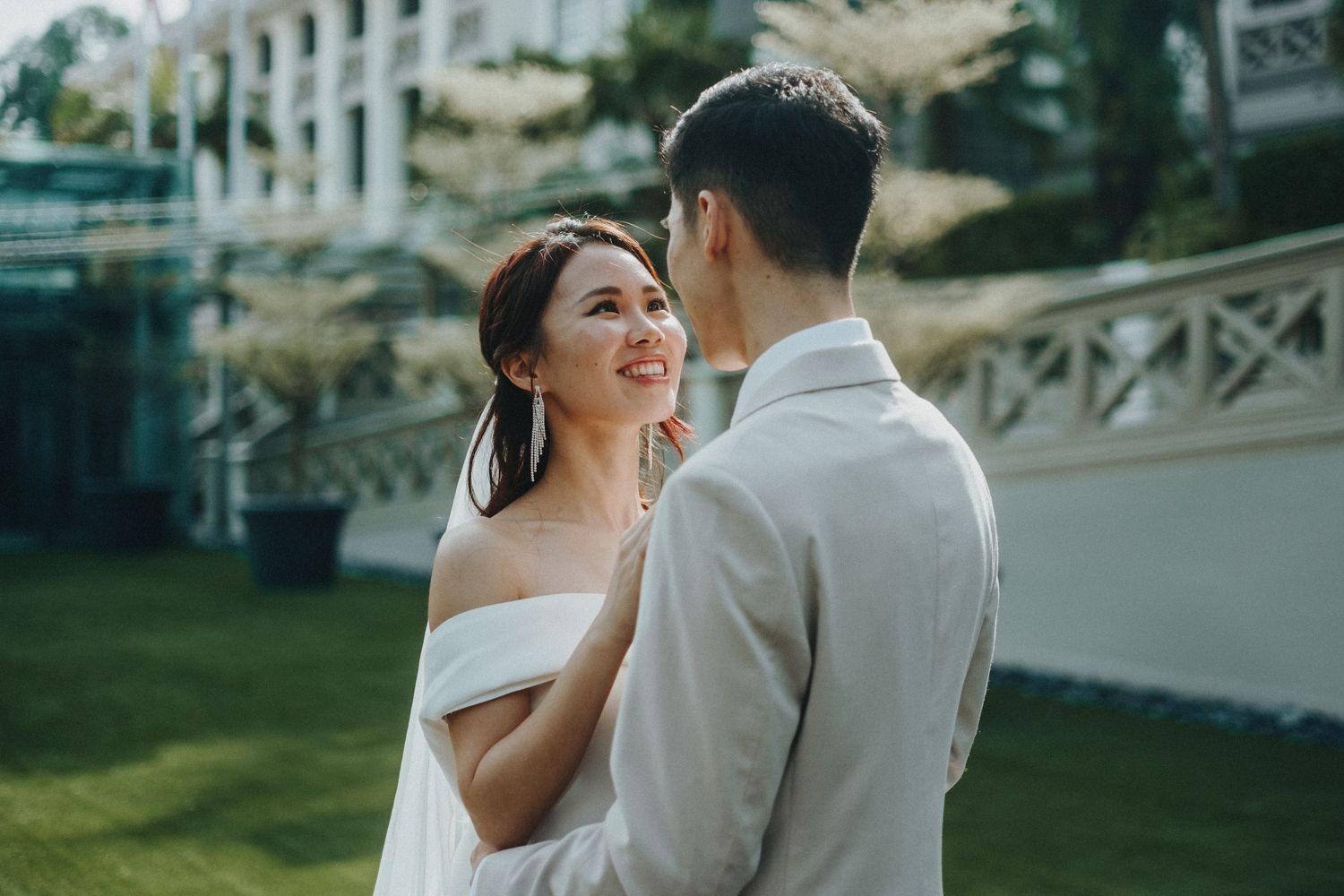 A couple shares a romantic moment outdoors during their wedding celebration on a manicured lawn.