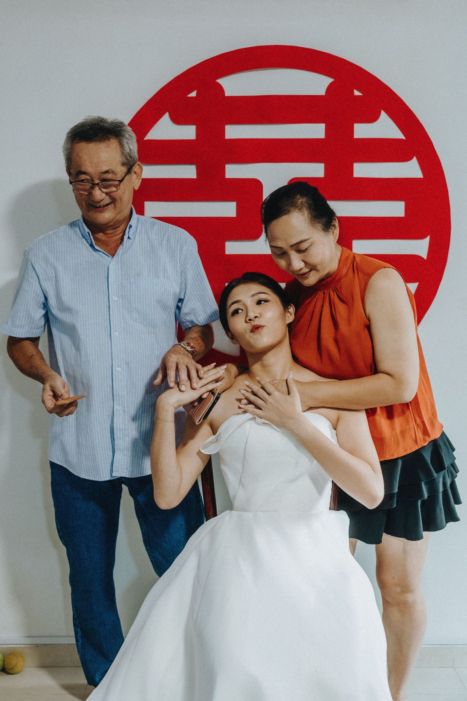 A heartwarming series of candid moments showing playful interactions against a white wall with traditional double happiness symbol.
