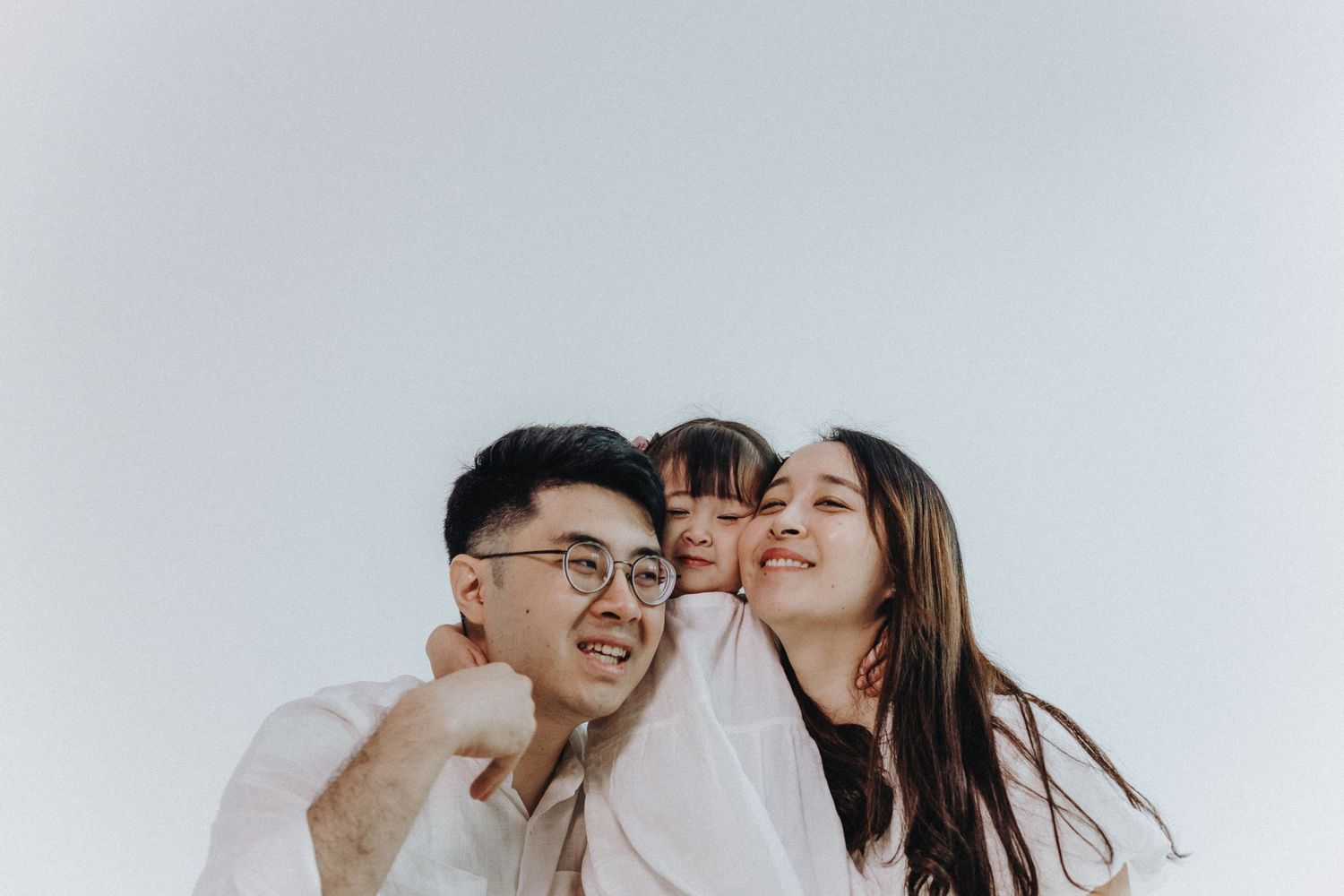 Close-up family portrait shows joyful expressions against white backdrop.
