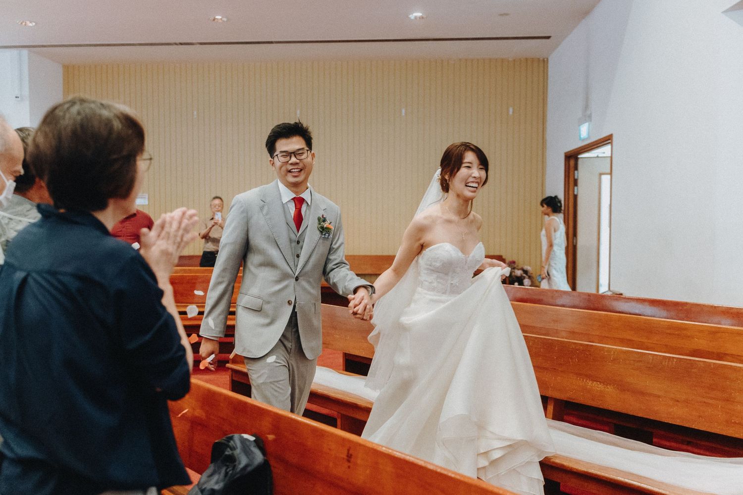 Newlyweds walking down church aisle while guests celebrate.