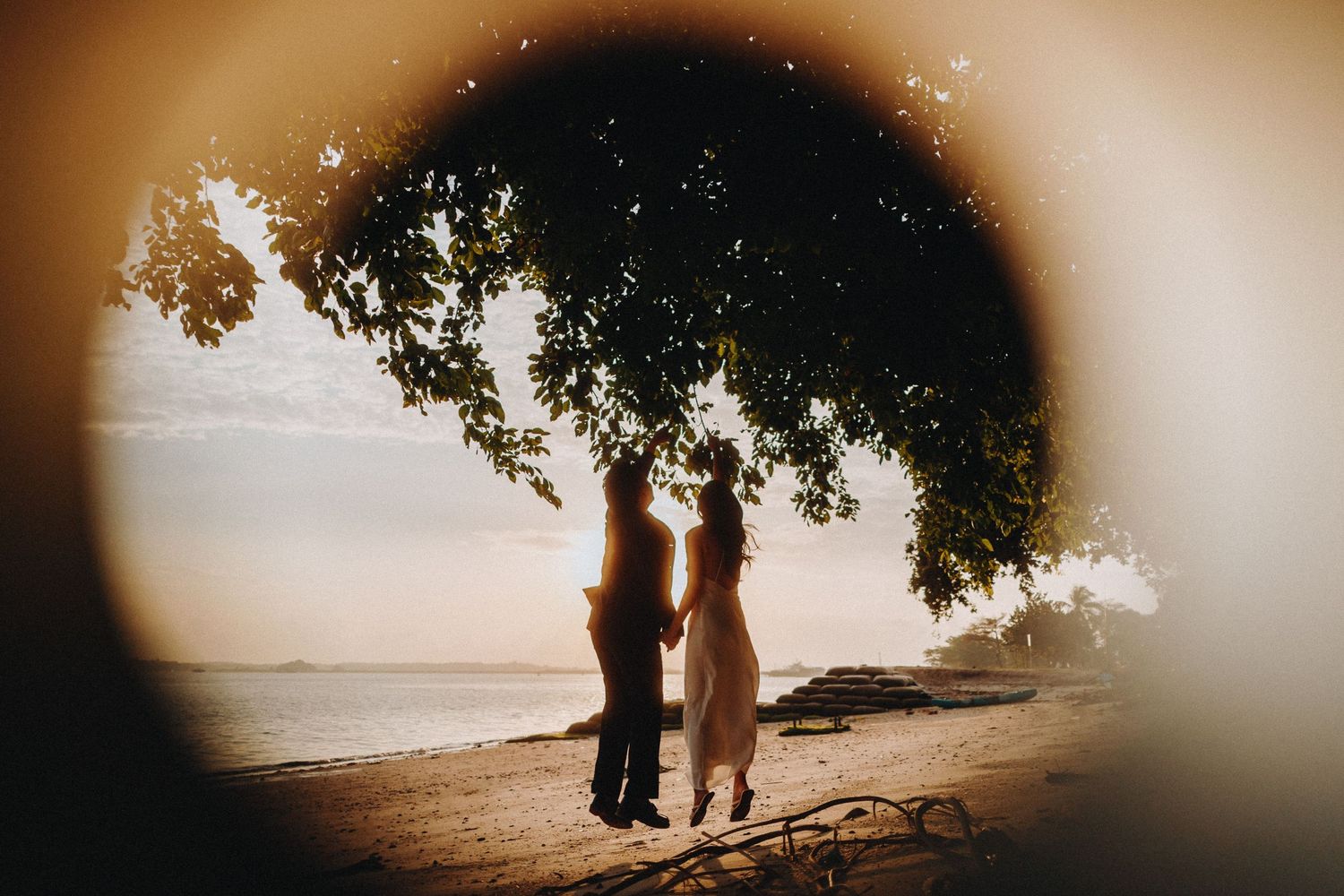 Romantic couple enjoying a golden sunset on a beach with soft vignette edges.