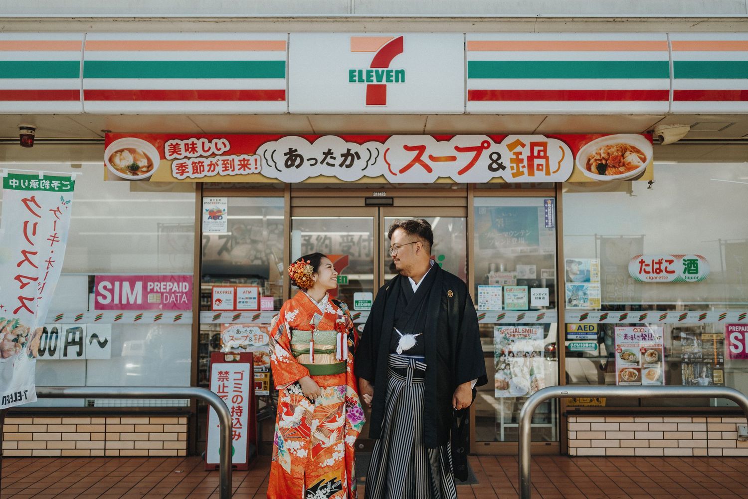 Couple in traditional Japanese attire posing outside a 7-Eleven store.