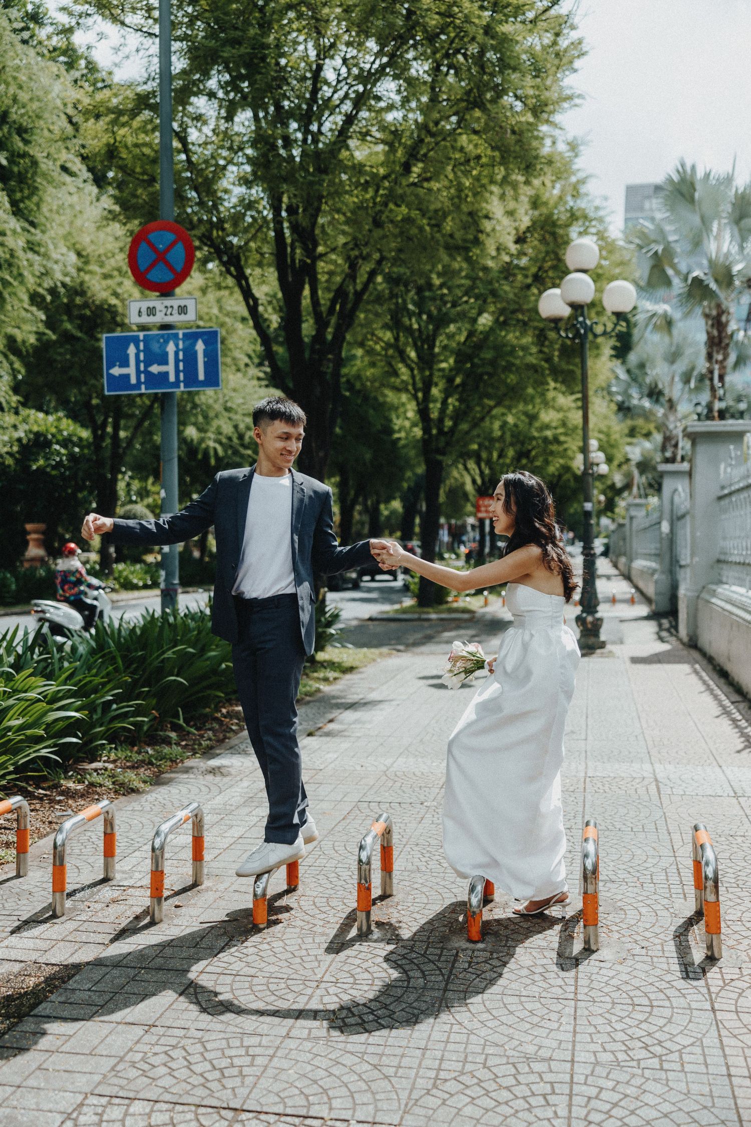 A series of fun wedding photos showing the couple dancing and spinning on a paved walkway between orange bollards.