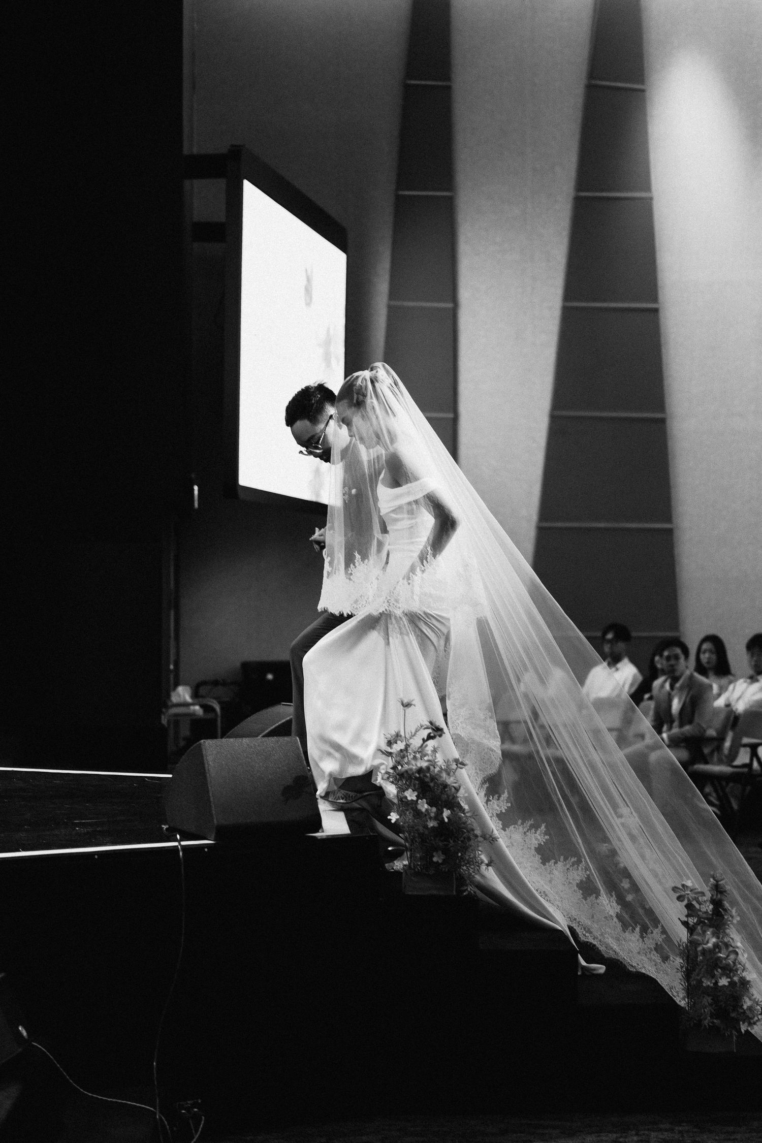 Black and white photo of bride in long veil at church ceremony.