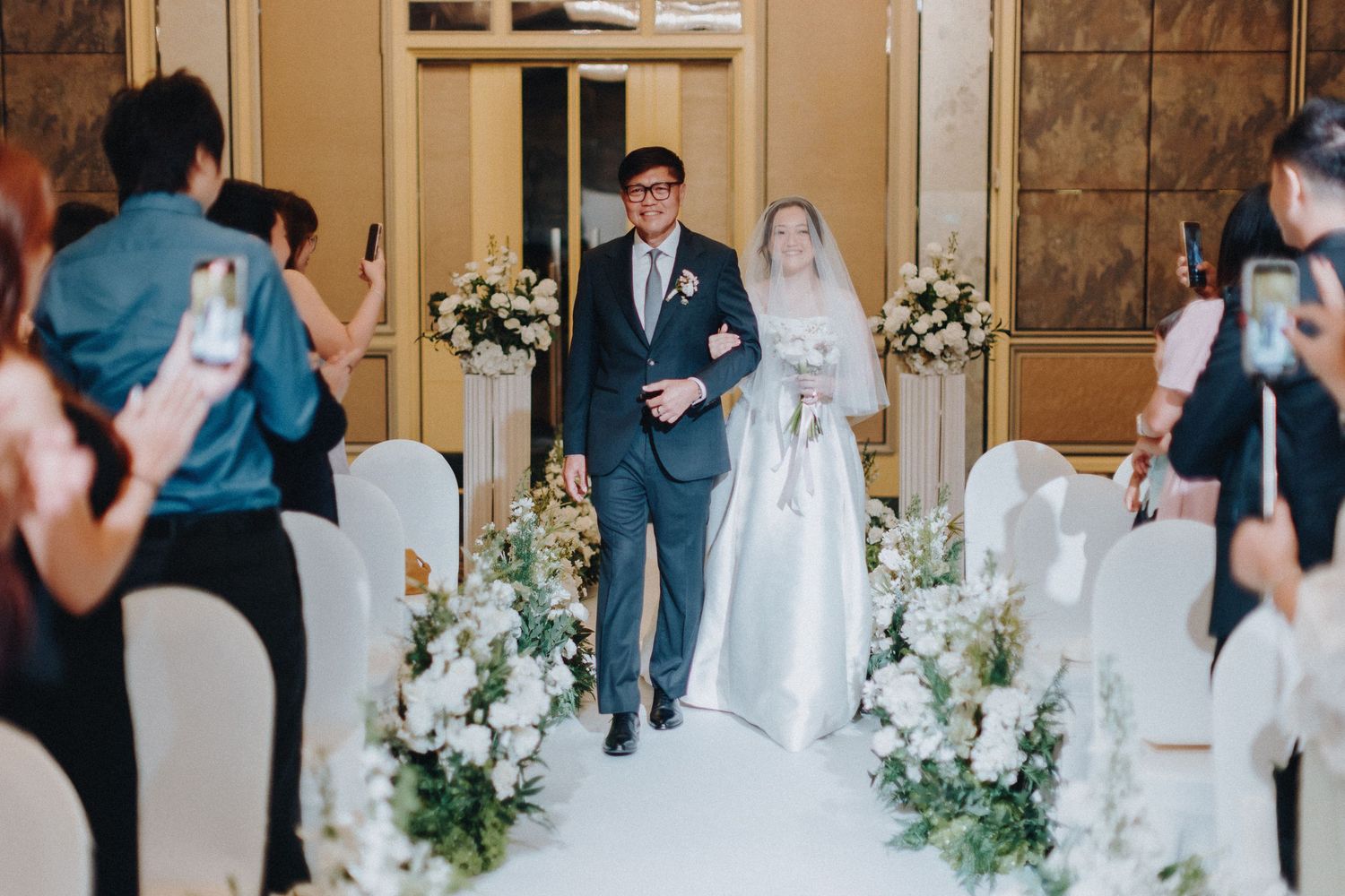 Wedding reception venue decorated with elegant white flowers and guests celebrating.