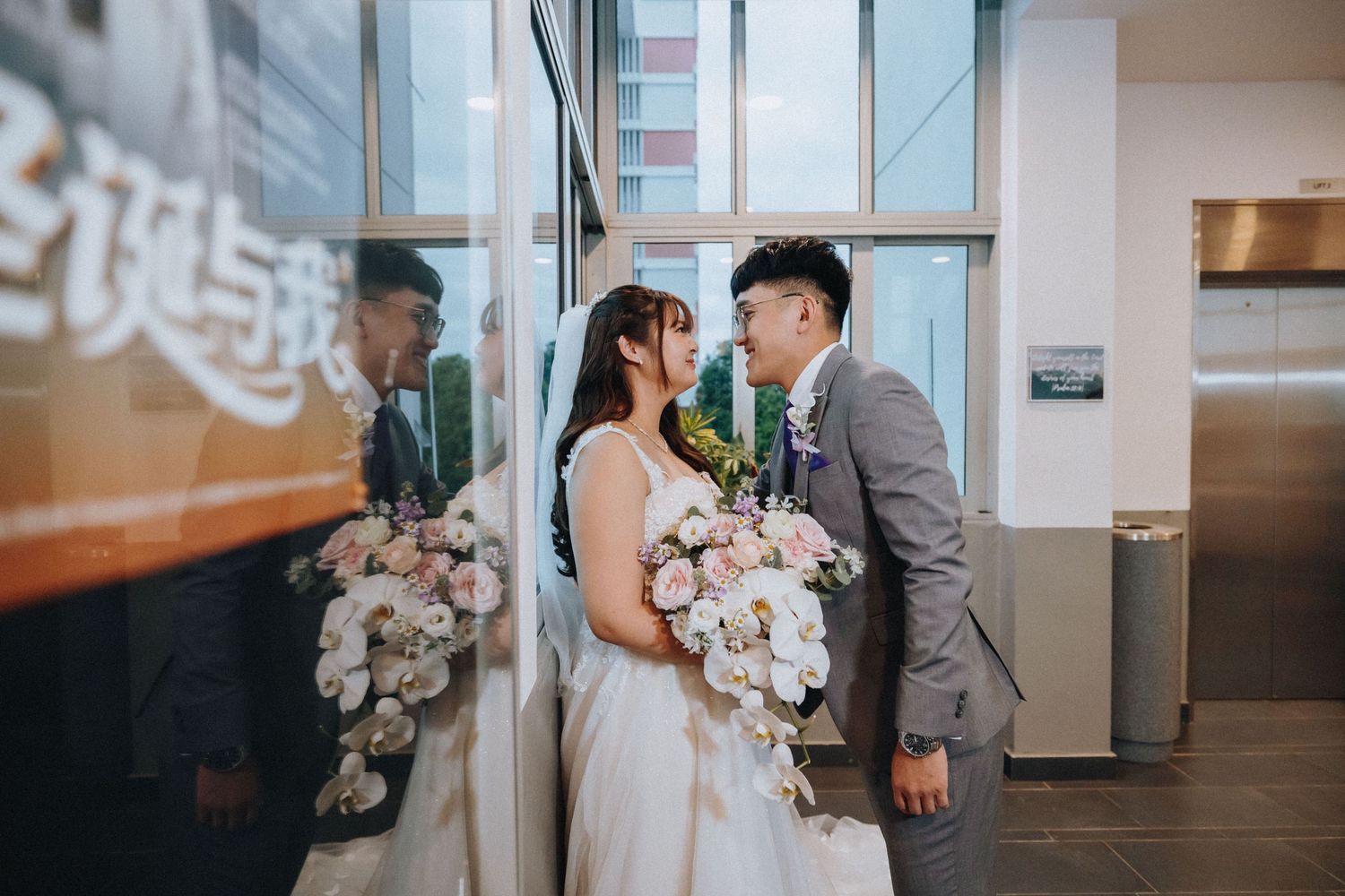 A wedding ceremony setup in a modern venue with white chairs and floral arrangements.