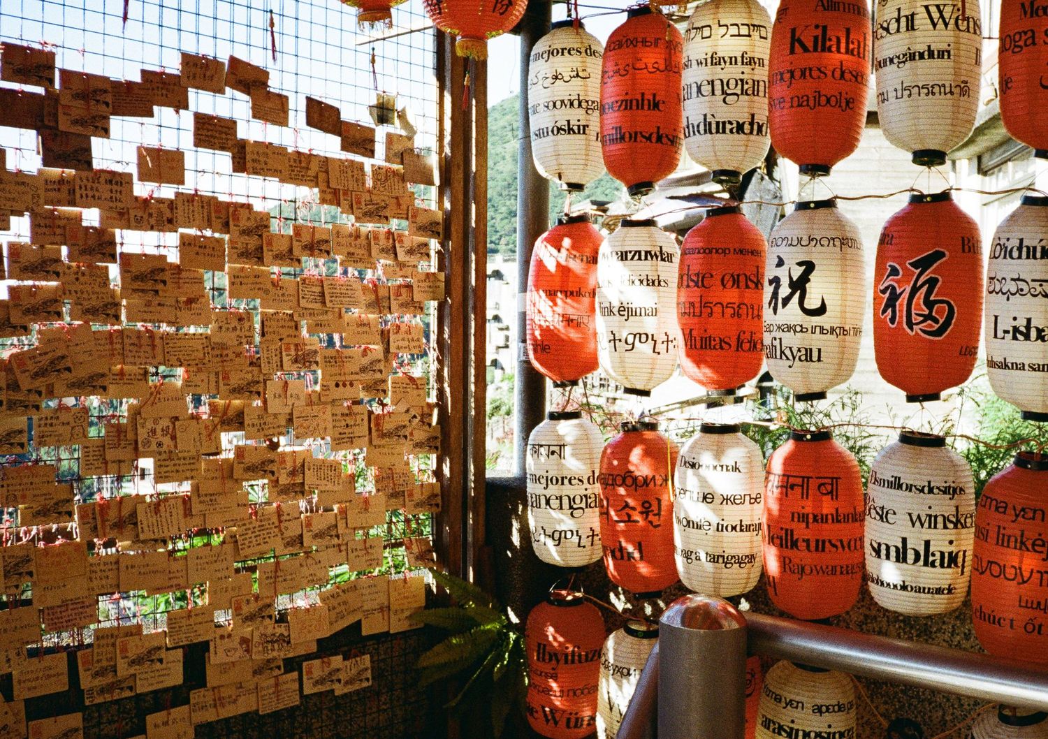 Red and white paper lanterns hanging against a brick wall in an Asian setting.