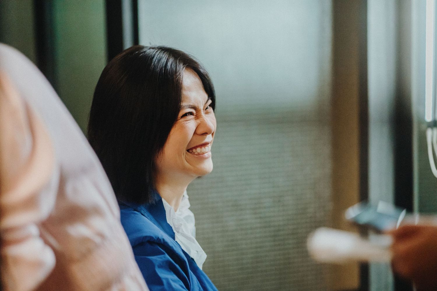 A professional wearing a blue blazer and white shirt smiles warmly during a business meeting.