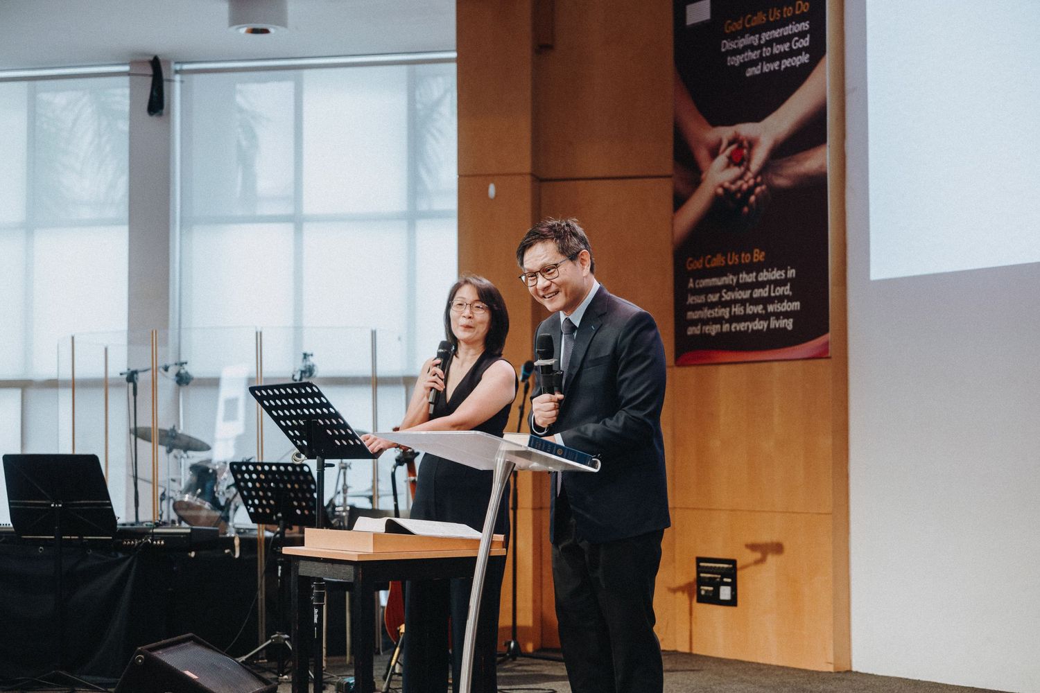 Two people stand behind a podium during what appears to be a wedding ceremony or presentation.