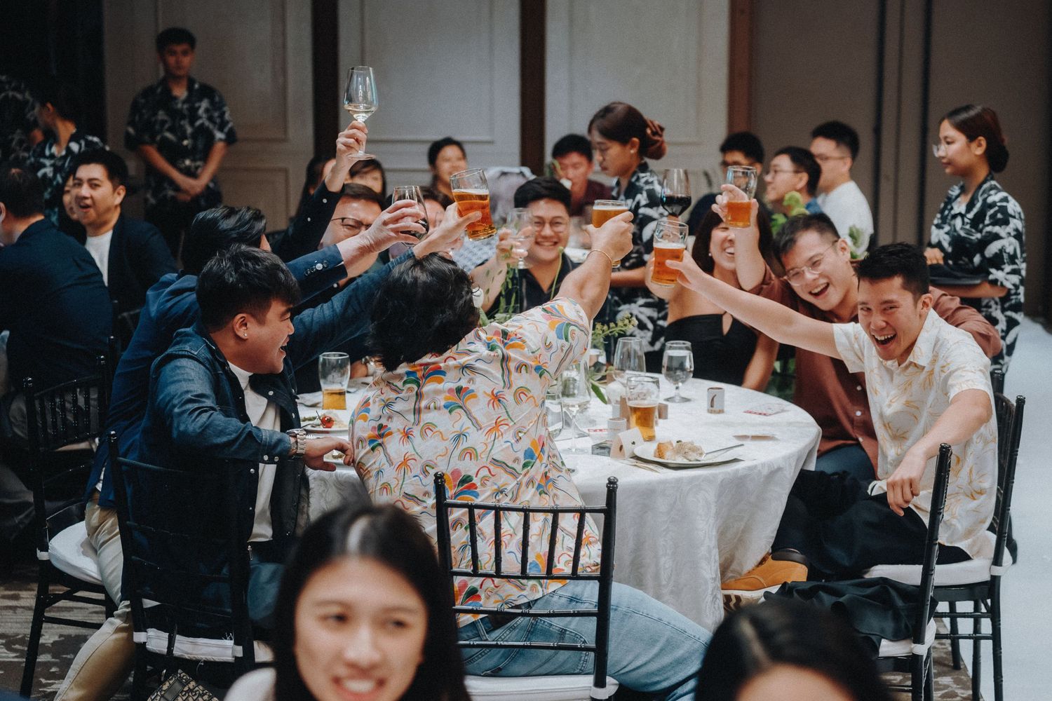 Wedding reception guests celebrating at round tables with formal place settings.