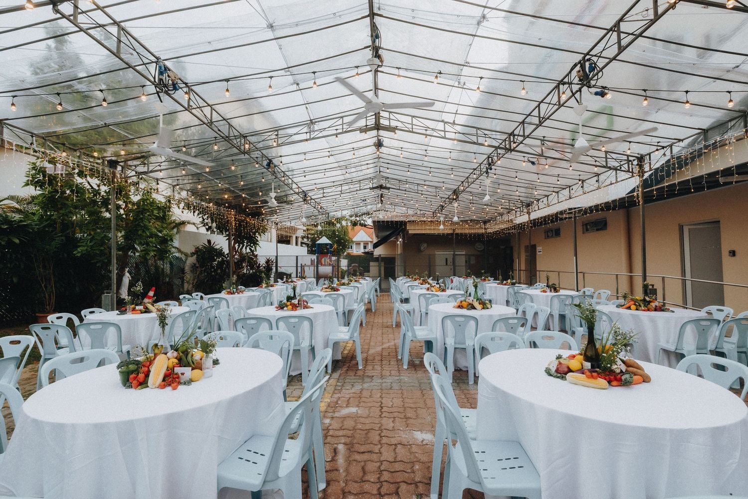 Wedding reception venue with white tablecloths and clear tent ceiling.