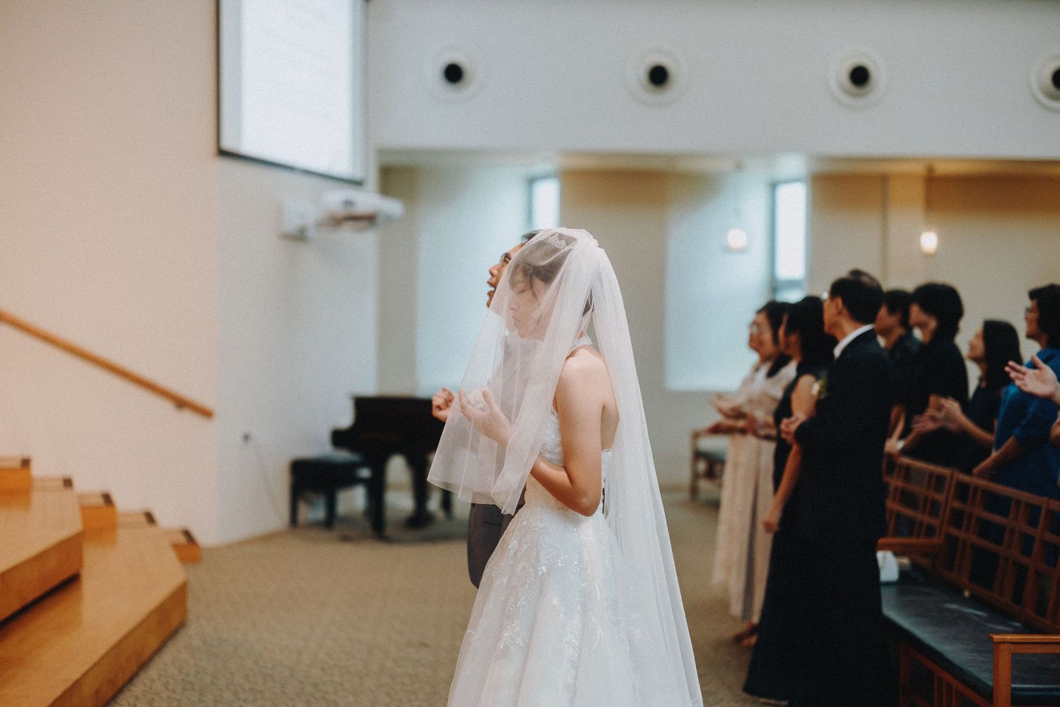 Modern church interior with white walls and wooden pews during a wedding ceremony.