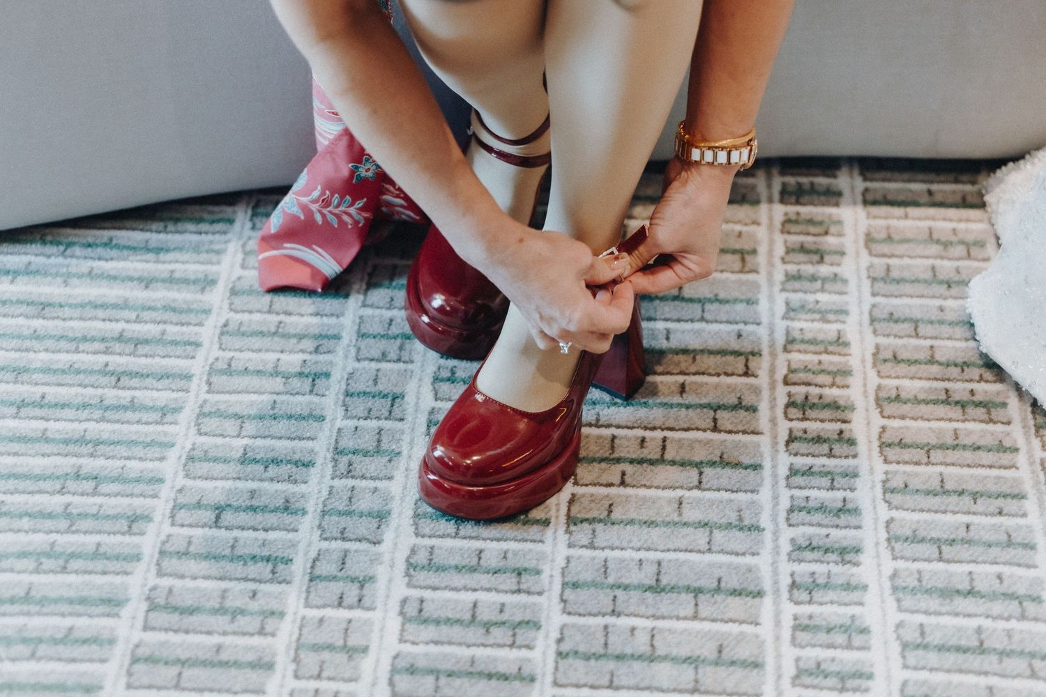 Close-up view of formal shoes and wedding attire on textured pavement.