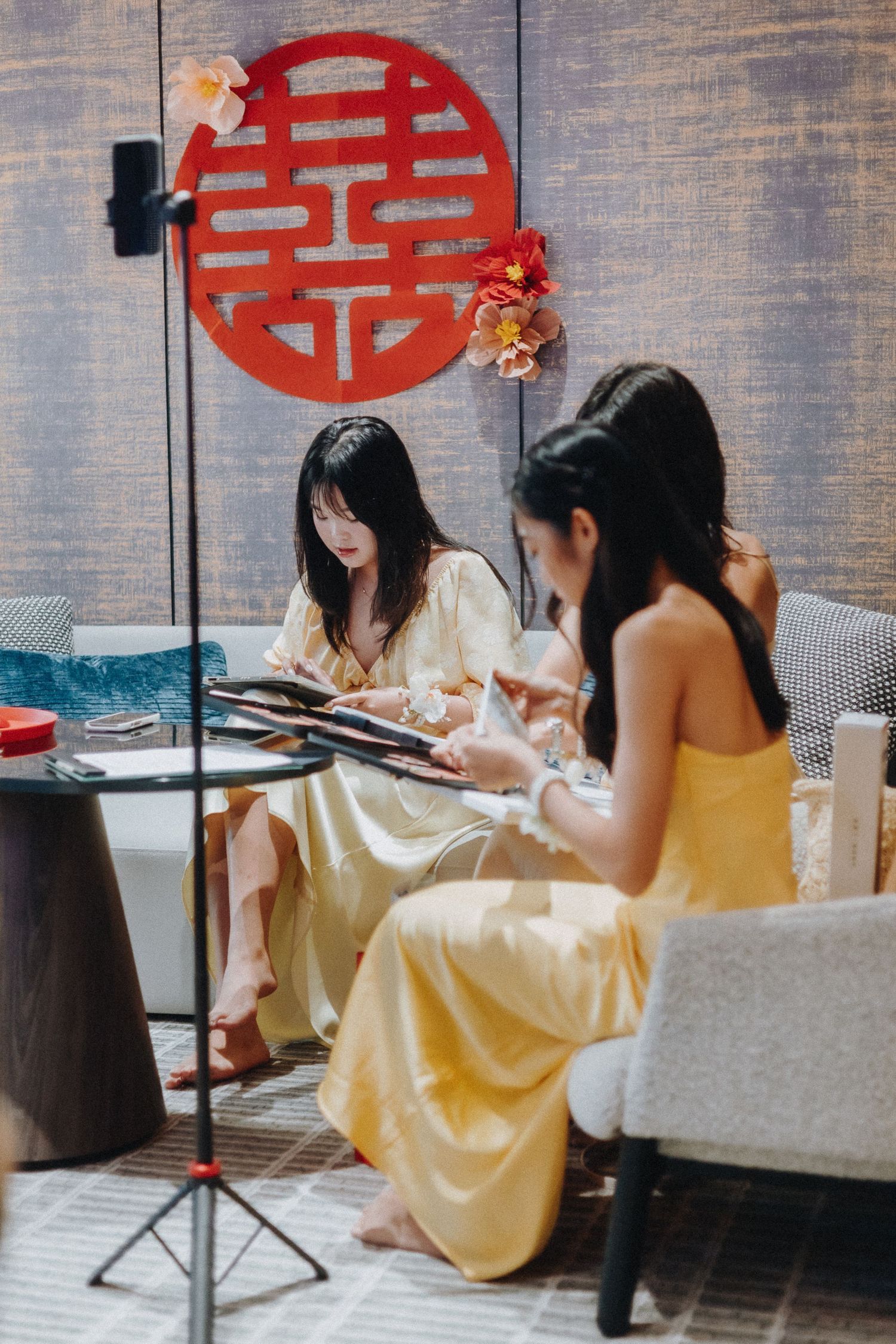 Four women in yellow dresses sit at tables in a modern restaurant with traditional Chinese decor.