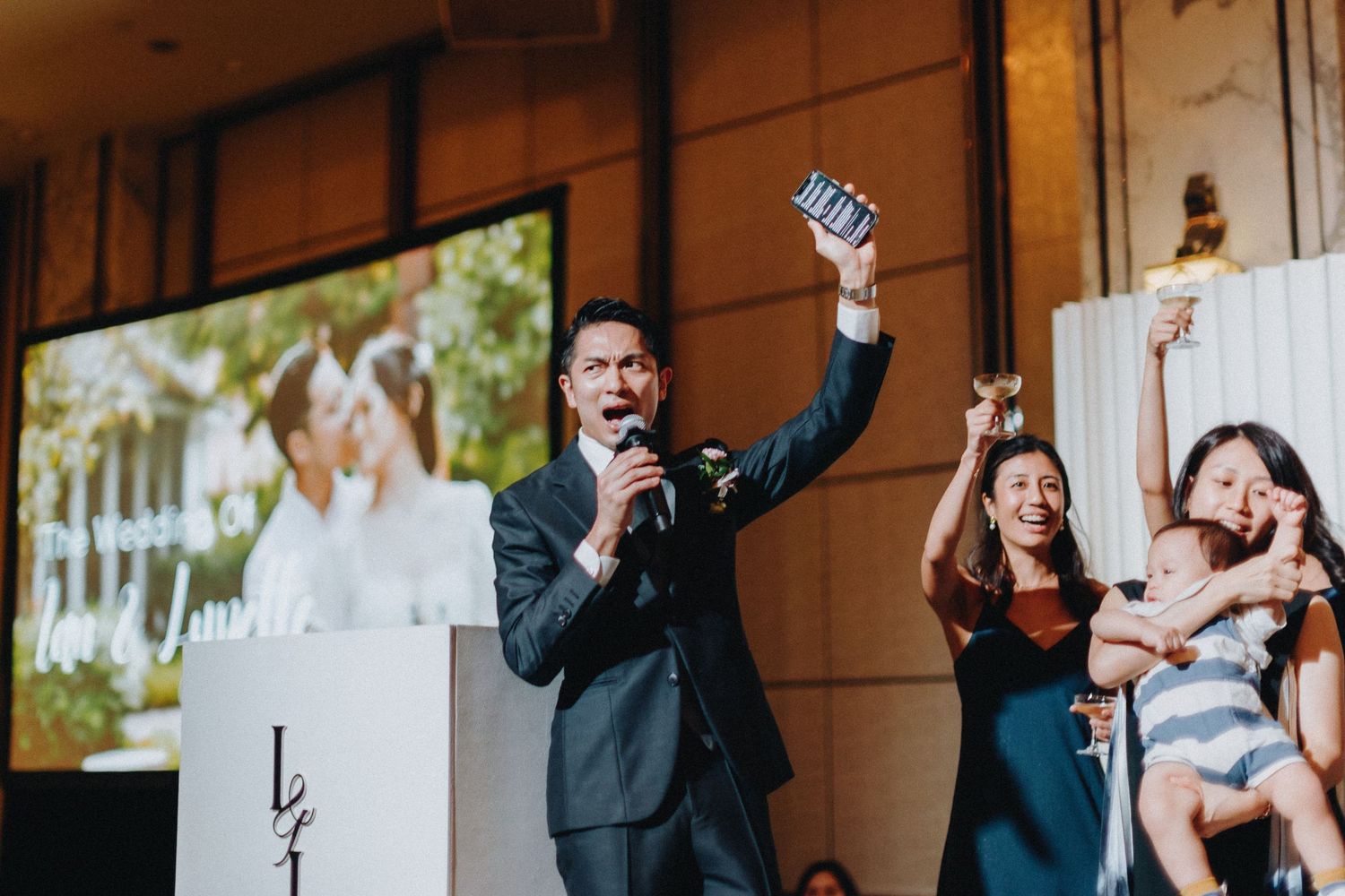 Wedding party members celebrating and raising hands in joyful poses outdoors.