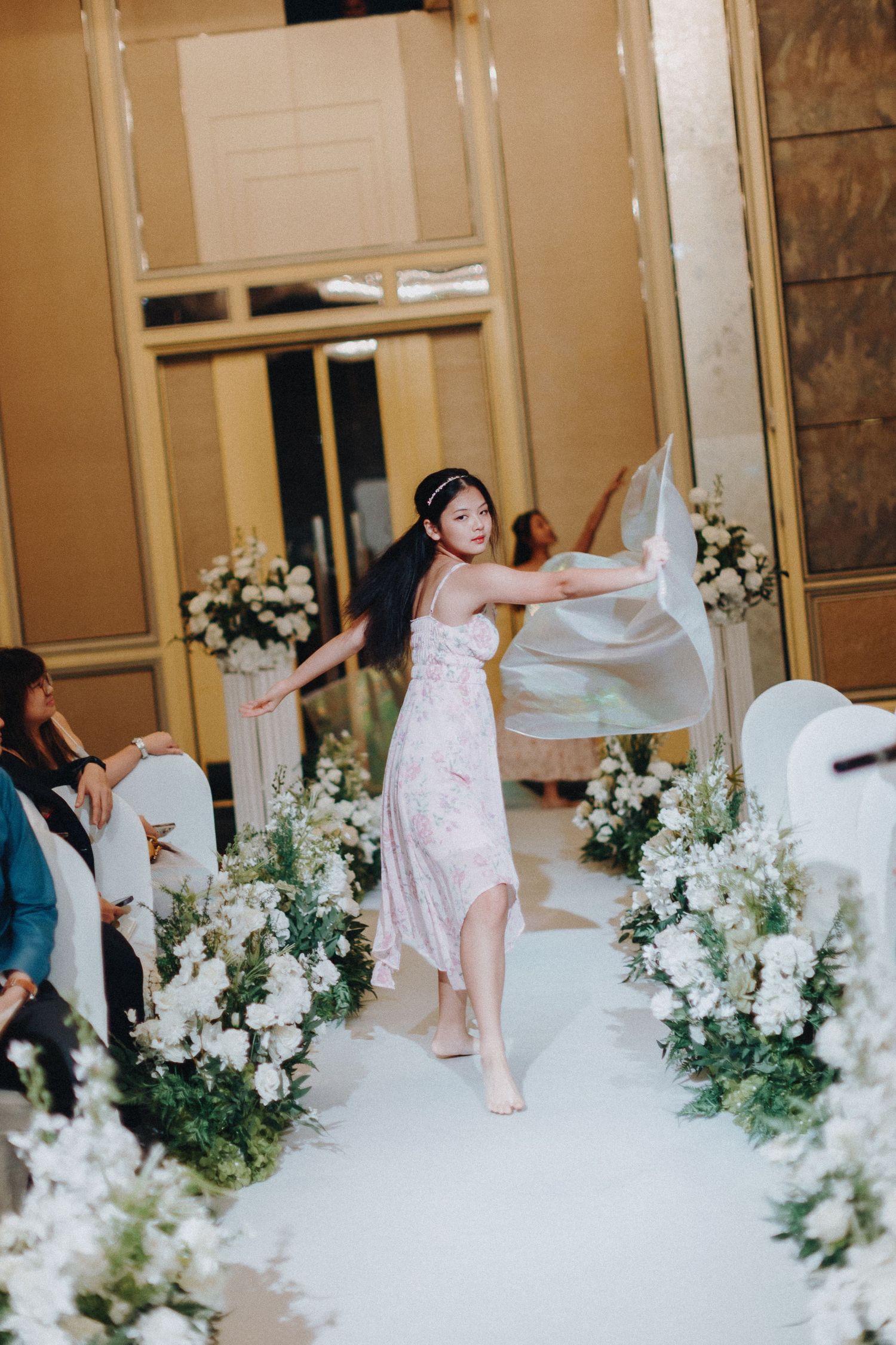 Wedding party dancing and celebrating with white floral decorations in an elegant ballroom.