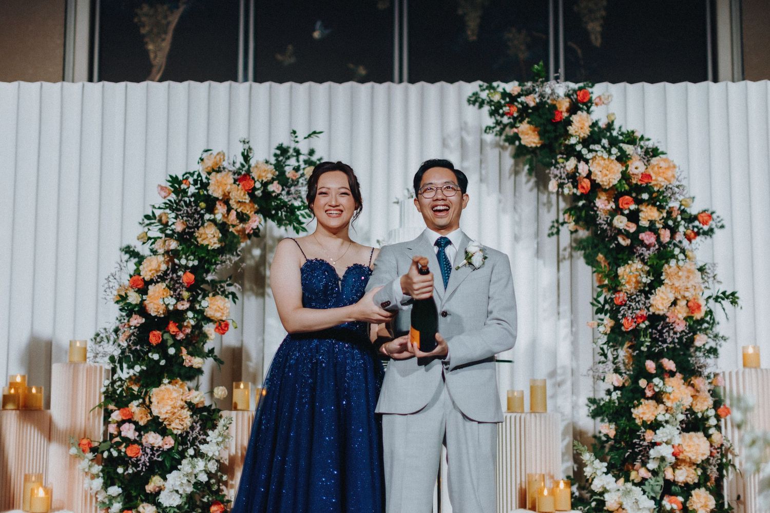 Wedding celebration with elegant floral arrangements and white panel backdrop.