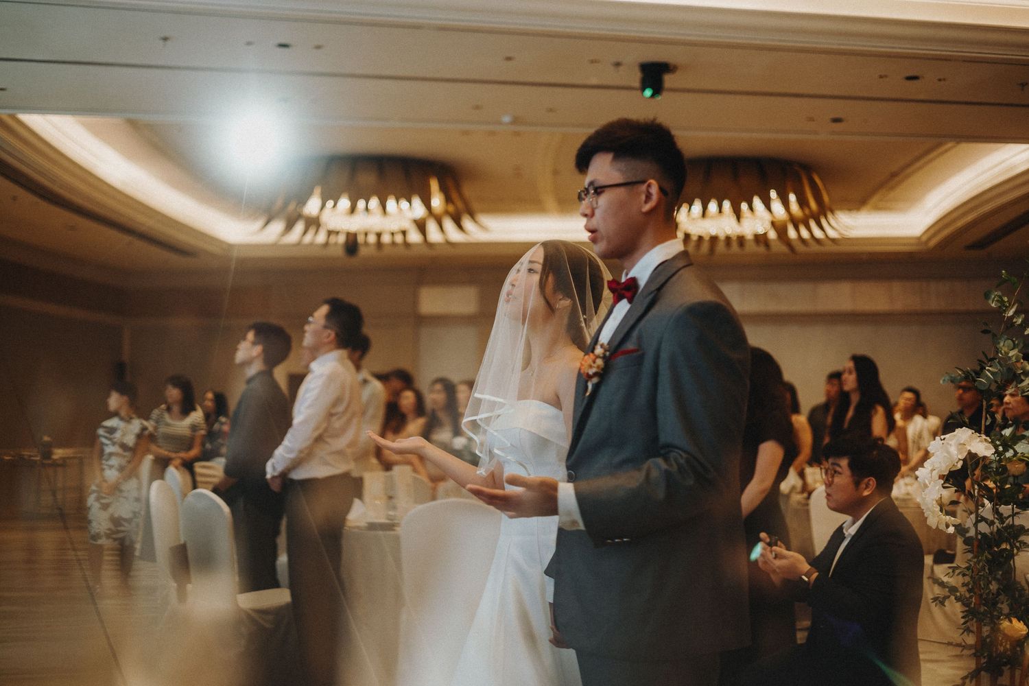 Wedding reception celebration in a grand ballroom with chandeliers and festive atmosphere.