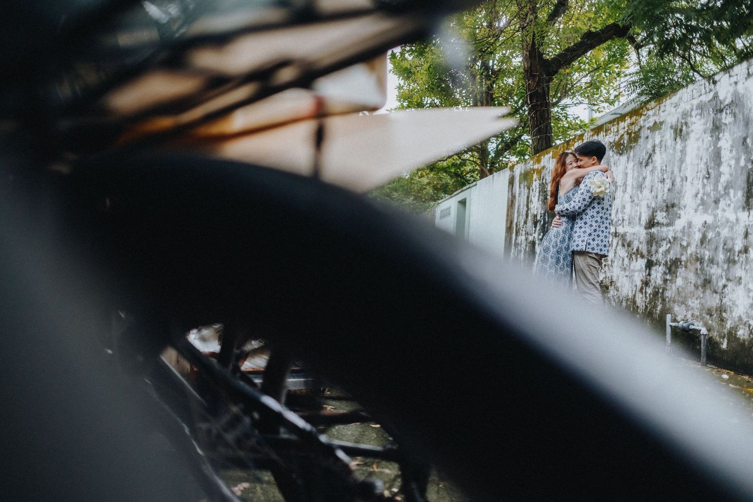 Love-filled moment captured through foliage and branches in a natural outdoor setting.