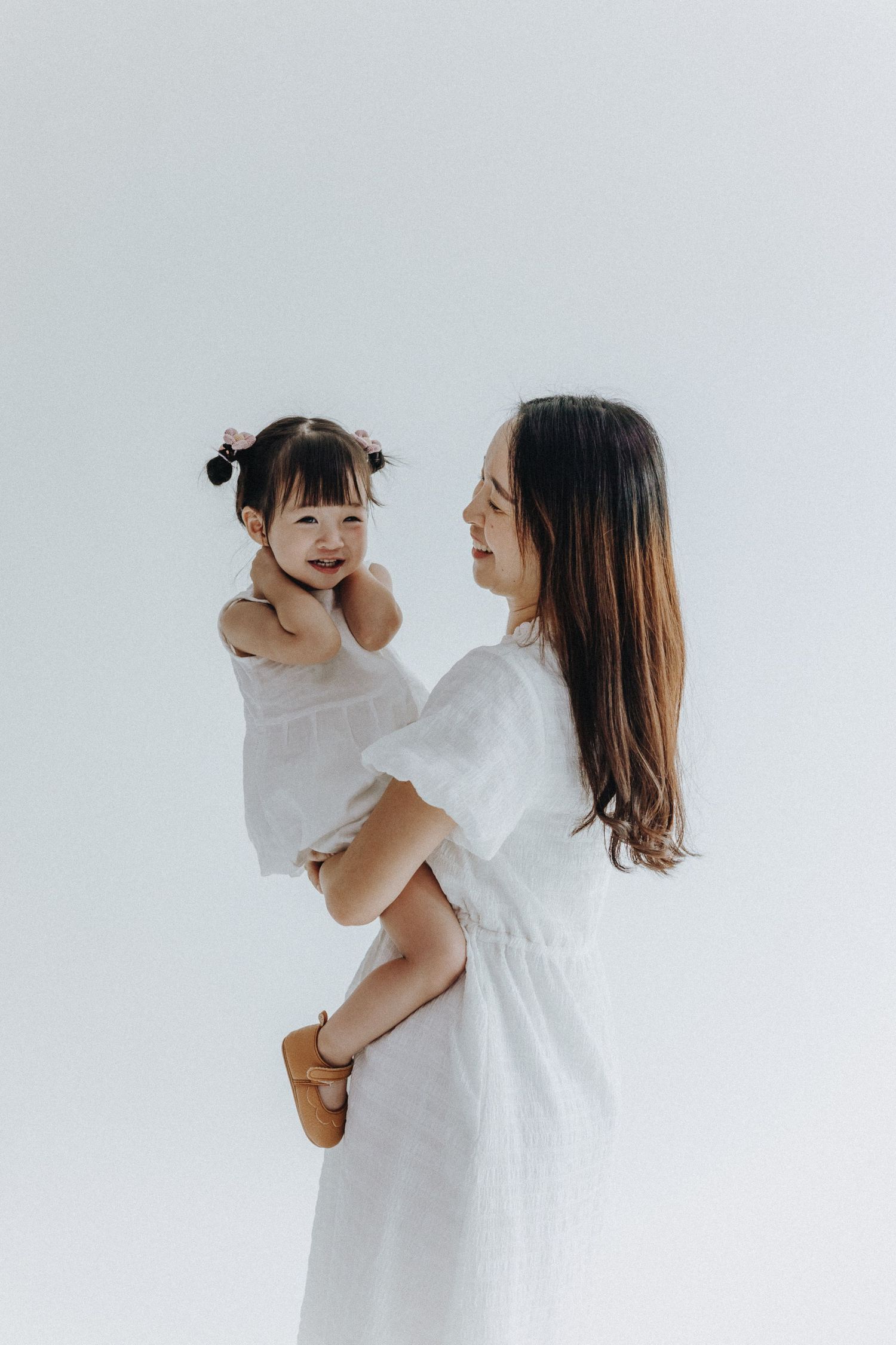 A series of gentle moments between parent and child in white clothing against a light background.