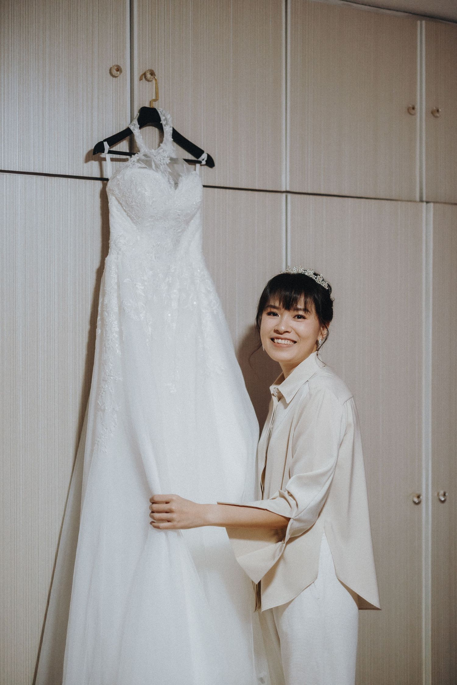 Aesthetic sequence of a white wedding dress hanging against a minimalist interior wall.