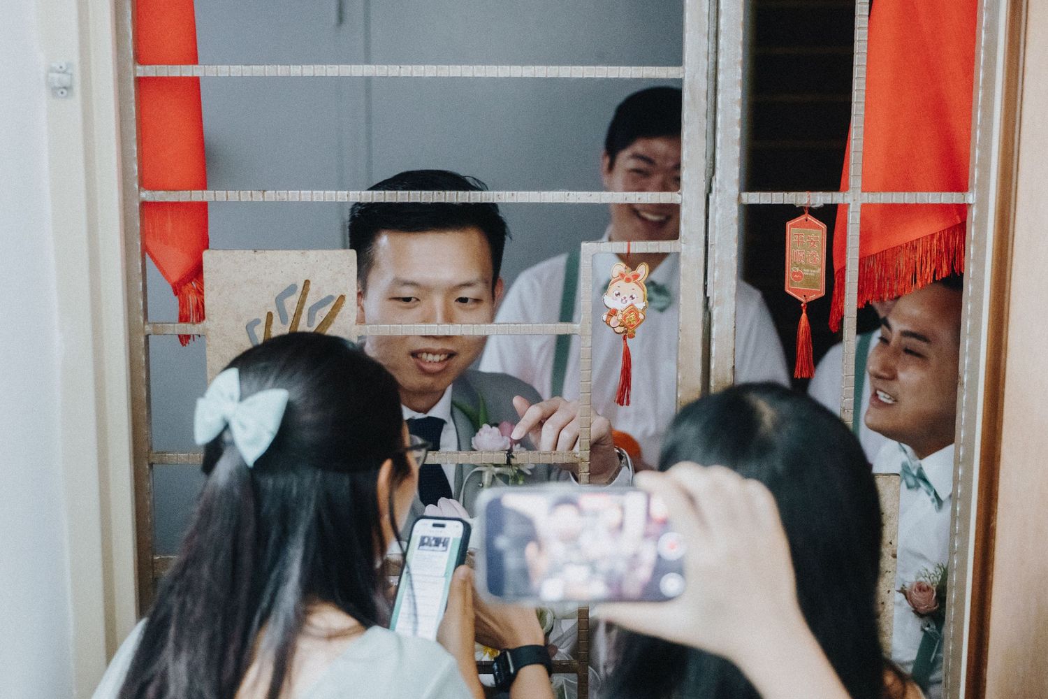 People celebrating behind a door frame while someone captures photos on their phone.