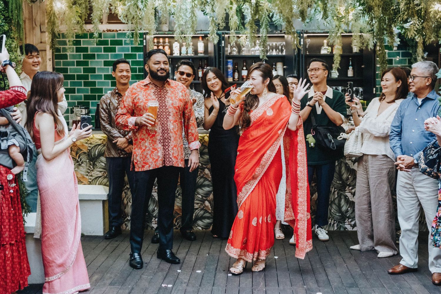 Guests in colorful traditional attire celebrate at an Indian wedding reception on a decorated outdoor deck.