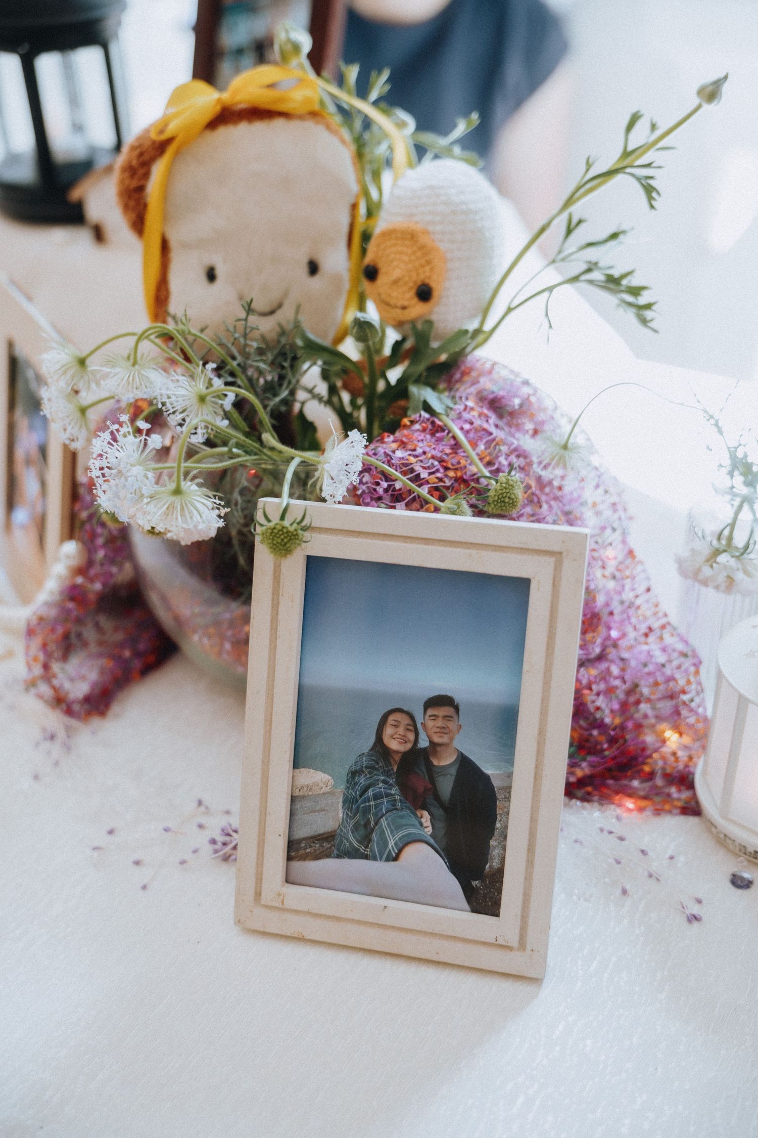 Framed couple photo displayed on a wedding table with floral centerpiece and stuffed toys.