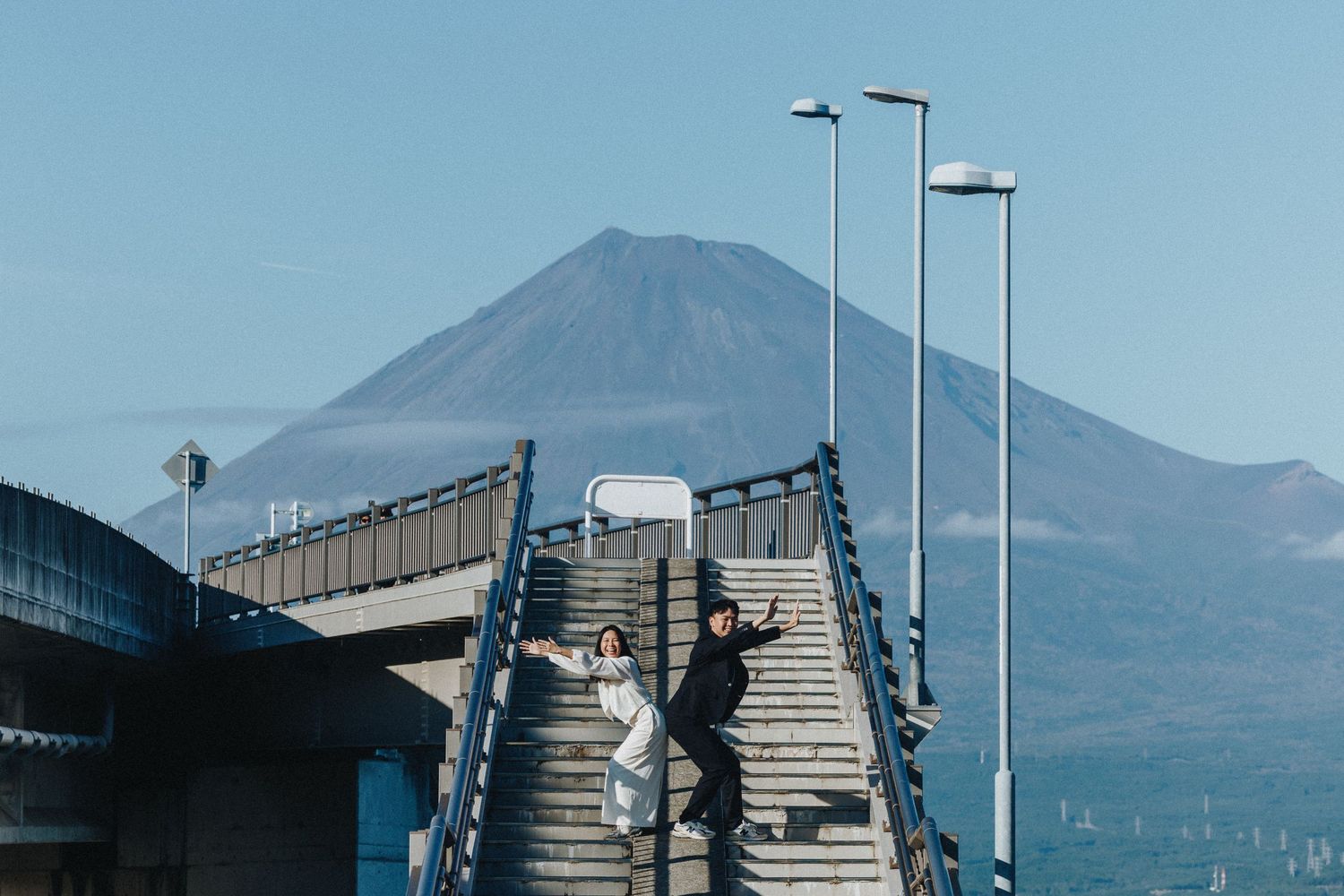Industrial steel bridge structure against blue sky with mountain silhouettes in the distance.