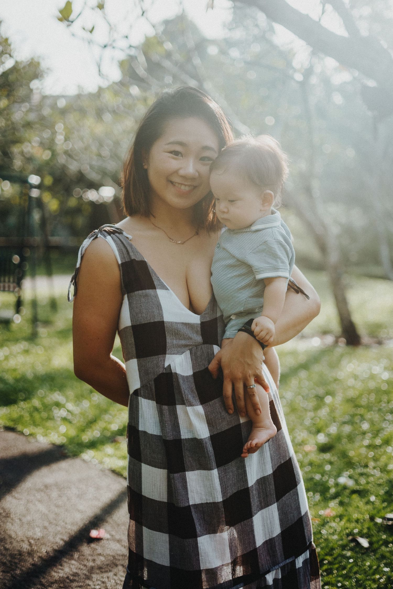 A mother and baby pose together outdoors wearing matching black and white checkered outfits.