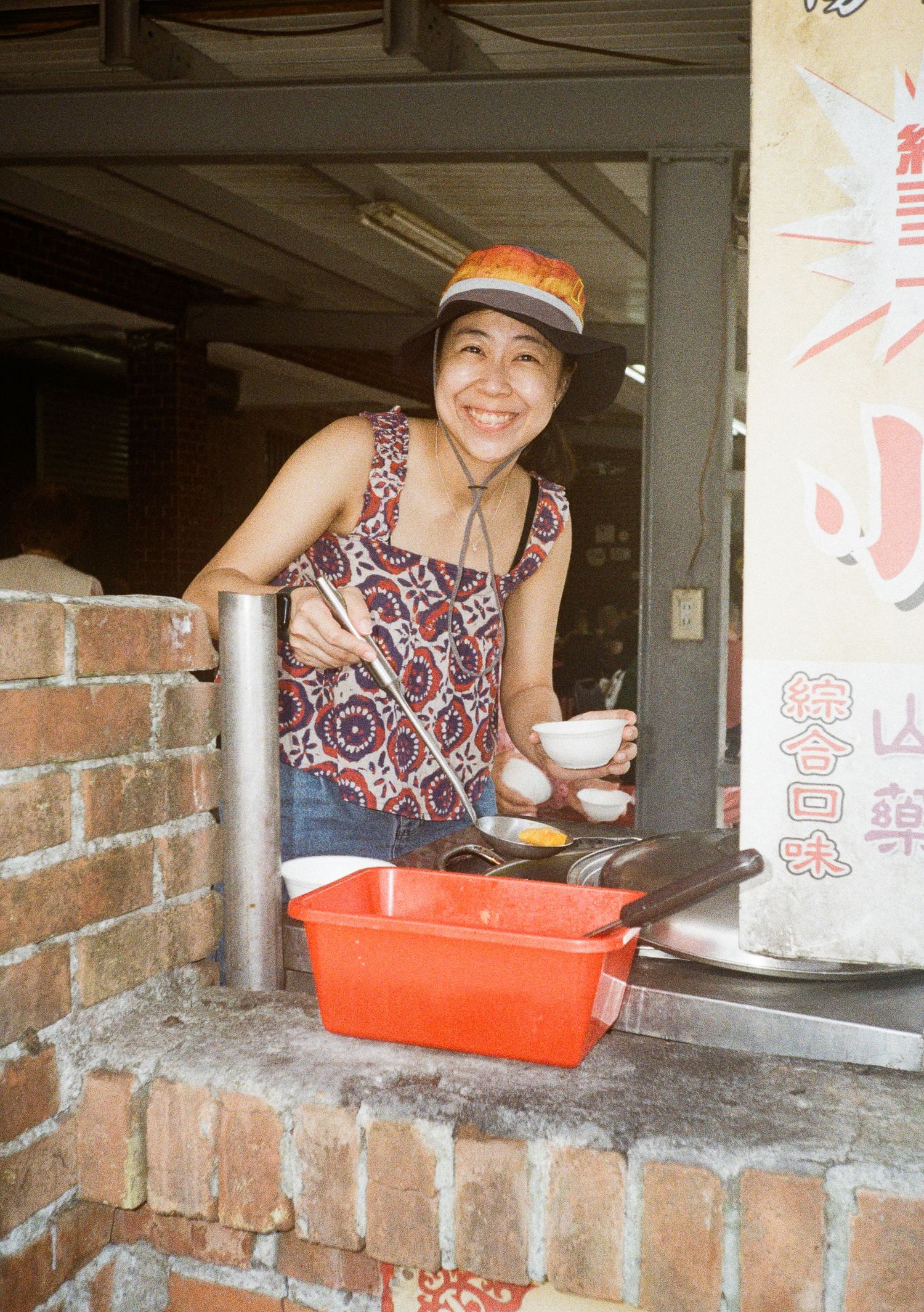 Small service window at a brick restaurant with red plastic tray and Chinese decorations.