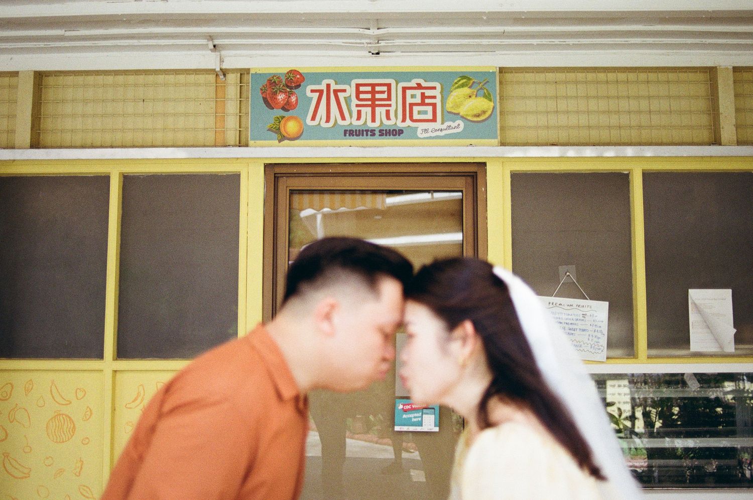 A romantic moment shared between a couple in front of an Asian storefront.