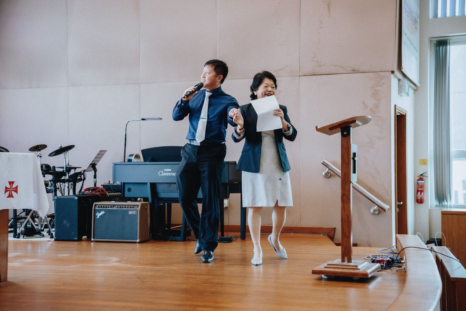 Two officiants performing during wedding ceremony on church stage.