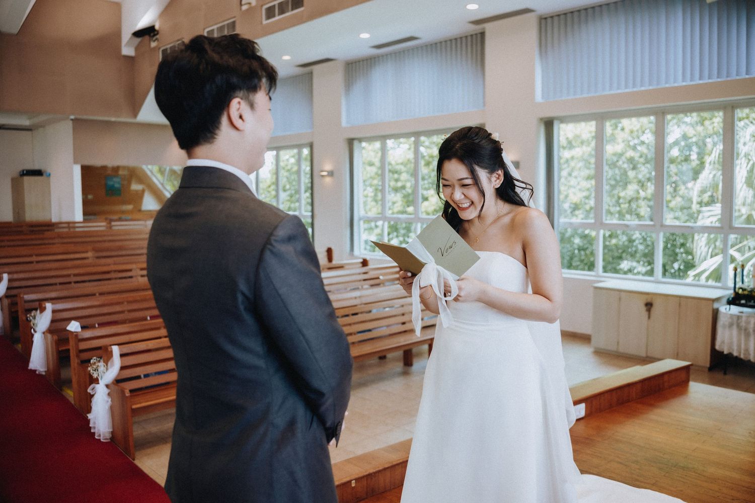 Bride and groom exchange heartfelt vows in a sunlit wooden church during wedding ceremony.