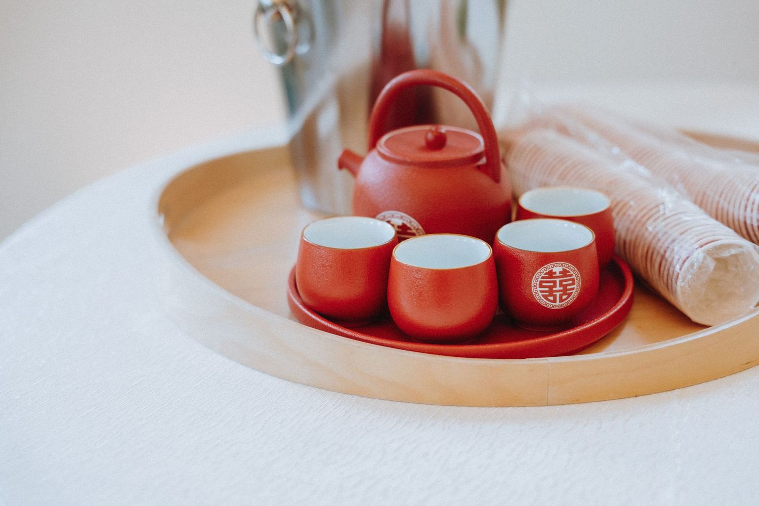 Traditional Chinese red tea set with teapot and four cups on a wooden tray for a wedding tea ceremony.