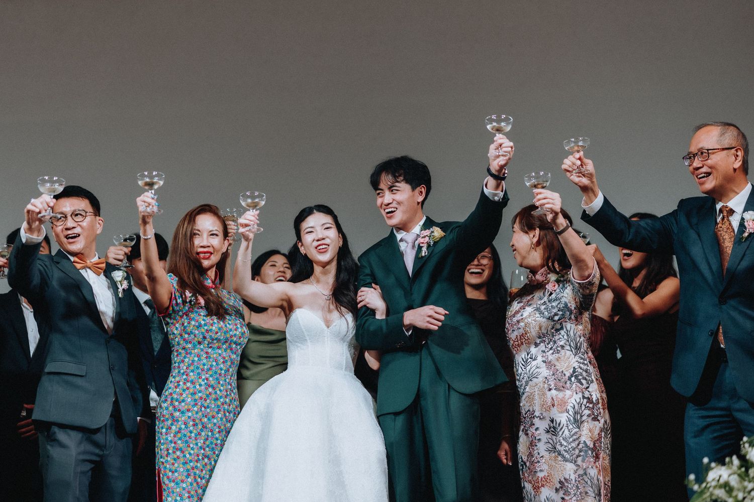A joyful wedding party raises champagne glasses in a celebratory toast with the bride and groom on stage.
