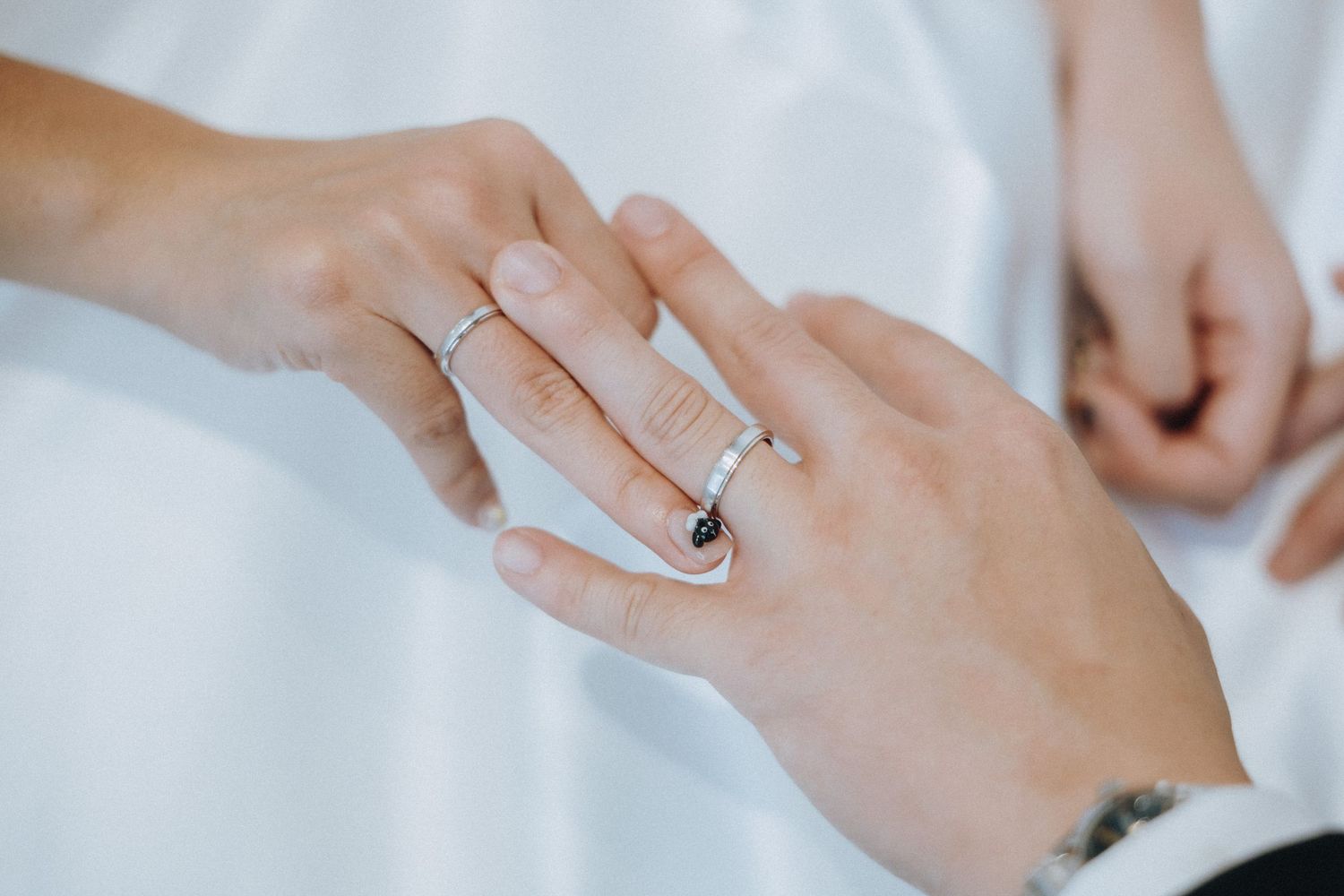 Close-up of a couple exchanging wedding rings, bride wearing a diamond band on her finger.